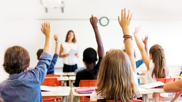 Teacher with students raising their hands